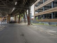 a long road in front of large building under an overpassy bridge at the end of a street