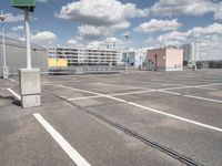 a parking lot in the city, with clouds and buildings in the background from across the street