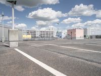 a parking lot in the city, with clouds and buildings in the background from across the street