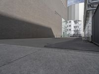 an empty sidewalk with a shadow on it and a building behind it in the background