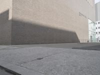 an empty sidewalk with a shadow on it and a building behind it in the background