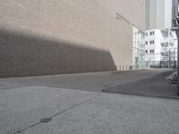 an empty sidewalk with a shadow on it and a building behind it in the background