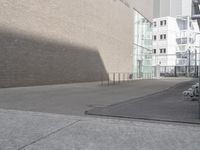 an empty sidewalk with a shadow on it and a building behind it in the background