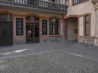 a cobble stone courtyard next to an empty building with the word kfc in german