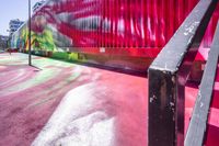 a painted stairway leading up to a ramp in front of a colorful building, with red curtain at the top