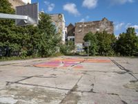 an empty basketball court in an abandoned city center area with graffiti on it and no people standing nearby