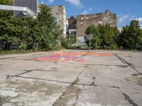 an empty basketball court in an abandoned city center area with graffiti on it and no people standing nearby