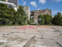 an empty basketball court in an abandoned city center area with graffiti on it and no people standing nearby