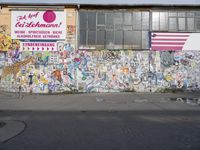 an image of graffiti on the side of a building with a flag in it, and a dog laying out on the sidewalk