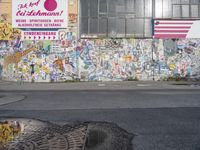 an image of graffiti on the side of a building with a flag in it, and a dog laying out on the sidewalk