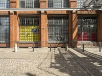 a brick building is painted bright yellow, and there are three benches next to the front door