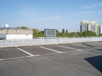 a parking lot full of cars on a clear day with buildings behind it on either side