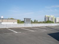 a parking lot full of cars on a clear day with buildings behind it on either side