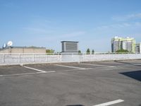 a parking lot full of cars on a clear day with buildings behind it on either side