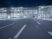 an empty parking lot at night with clear windows and parking lights on the side of it