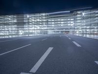 an empty parking lot at night with clear windows and parking lights on the side of it