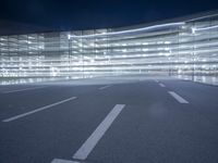 an empty parking lot at night with clear windows and parking lights on the side of it
