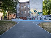 a basketball court and some graffiti on it in front of a building with trees and grass