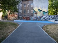 a basketball court and some graffiti on it in front of a building with trees and grass