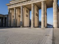 a large white building with pillars and some people walking around it and the ground with an open area