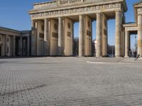 a large white building with pillars and some people walking around it and the ground with an open area