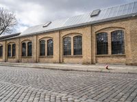 the street has bricks and windows along with a white sign that reads the train station