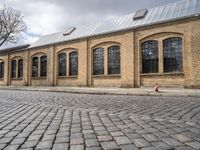 the street has bricks and windows along with a white sign that reads the train station