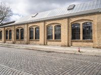 the street has bricks and windows along with a white sign that reads the train station