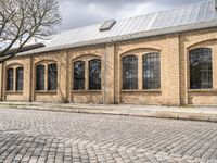 the street has bricks and windows along with a white sign that reads the train station