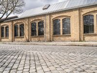 the street has bricks and windows along with a white sign that reads the train station