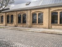 the street has bricks and windows along with a white sign that reads the train station