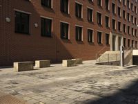 empty sidewalk outside the side of a brick building in a city setting on a sunny day