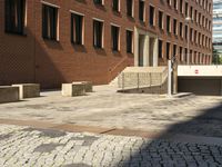 empty sidewalk outside the side of a brick building in a city setting on a sunny day