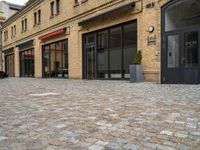 a bricked walkway on the outside of a building with two motorcycles parked near by