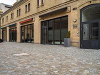 a bricked walkway on the outside of a building with two motorcycles parked near by