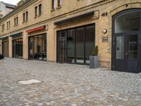 a bricked walkway on the outside of a building with two motorcycles parked near by