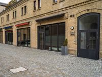 a bricked walkway on the outside of a building with two motorcycles parked near by