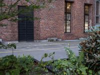 a fire hydrant is in front of a red brick building and shrubs around it