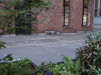 a fire hydrant is in front of a red brick building and shrubs around it