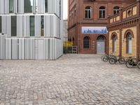 bicycles parked in front of two brick buildings, and the building is surrounded by several different windows