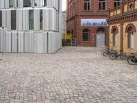 bicycles parked in front of two brick buildings, and the building is surrounded by several different windows