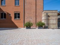 two planters are sitting in front of brick buildings on a sidewalk with blue sky