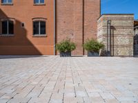 two planters are sitting in front of brick buildings on a sidewalk with blue sky