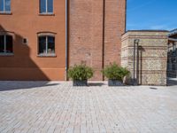 two planters are sitting in front of brick buildings on a sidewalk with blue sky