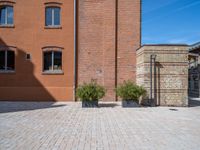 two planters are sitting in front of brick buildings on a sidewalk with blue sky