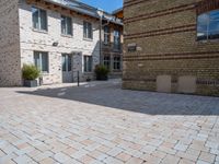 a brick paved courtyard has white windows, grey concrete pavers, and red bricks