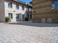 a brick paved courtyard has white windows, grey concrete pavers, and red bricks