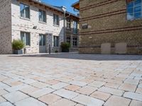 a brick paved courtyard has white windows, grey concrete pavers, and red bricks