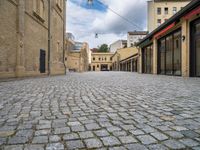 a brick road leads to several different stores in a european city with buildings behind it