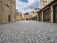 a brick road leads to several different stores in a european city with buildings behind it